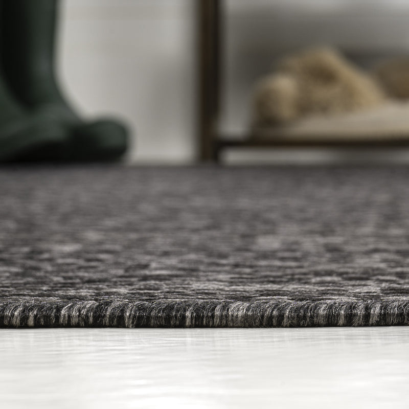 Textured black area rug surface with fine cream speckling