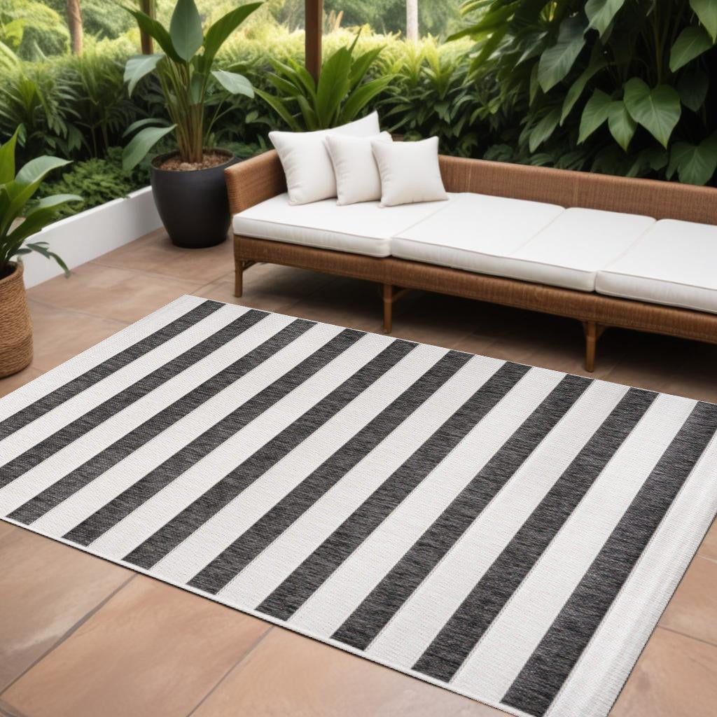 Striped indoor outdoor area rug with black and cream bands on patio
