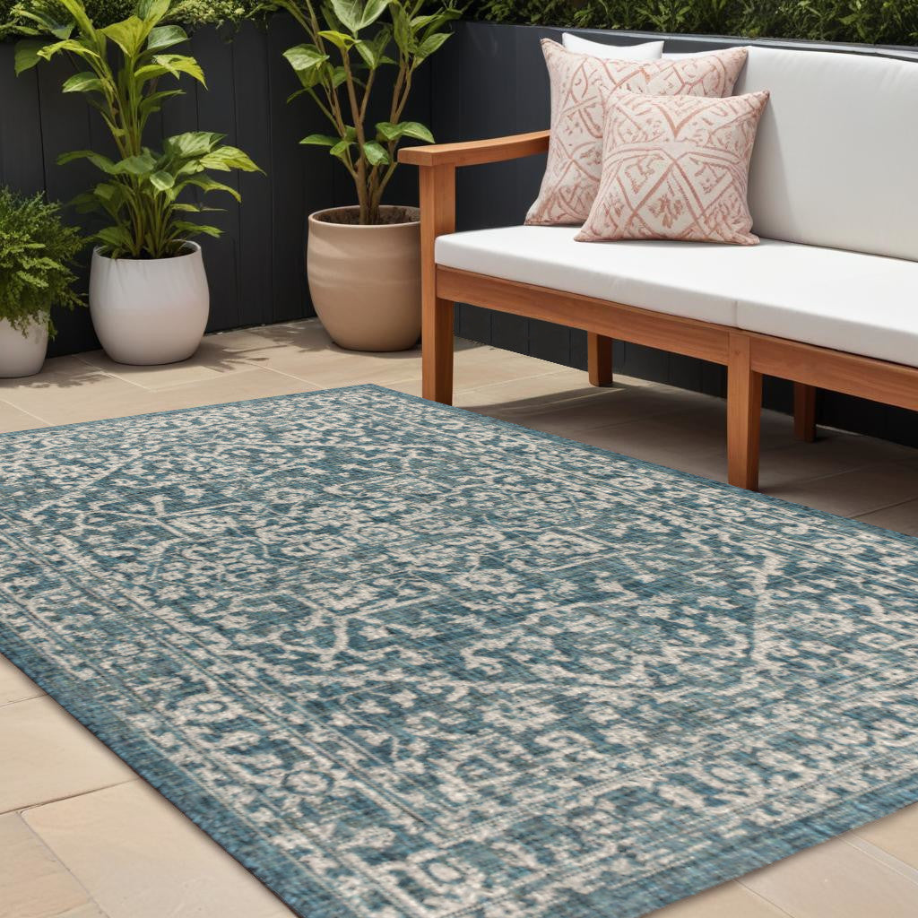 Teal blue area rug with gray medallion pattern on patio tiles