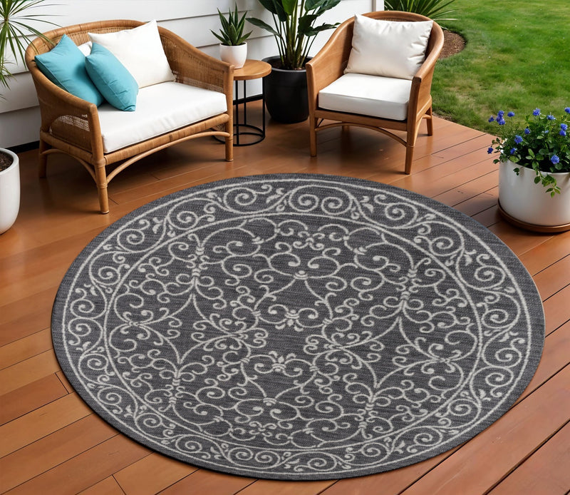 Round indoor outdoor area rug with dark gray base and light gray ornamental medallion