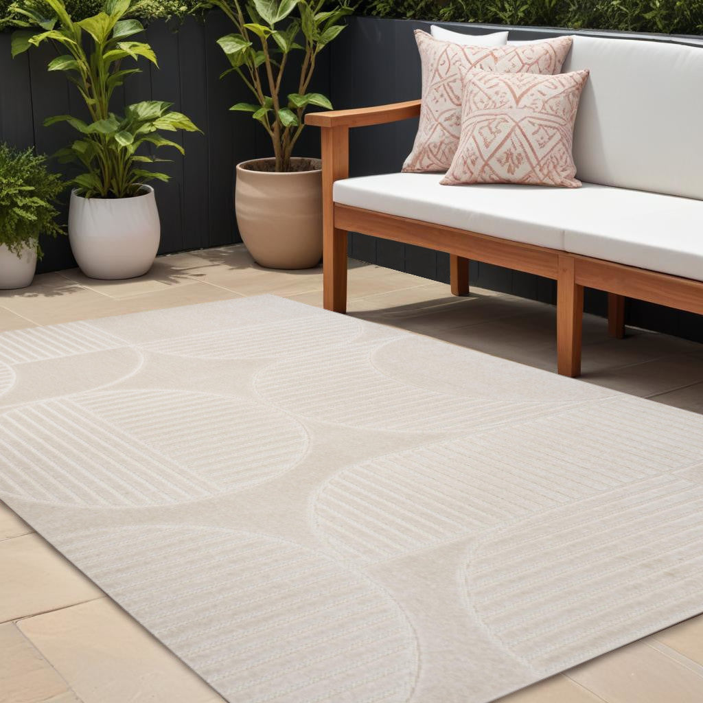 Ivory and cream indoor outdoor area rug with striped oval motif and textured low pile