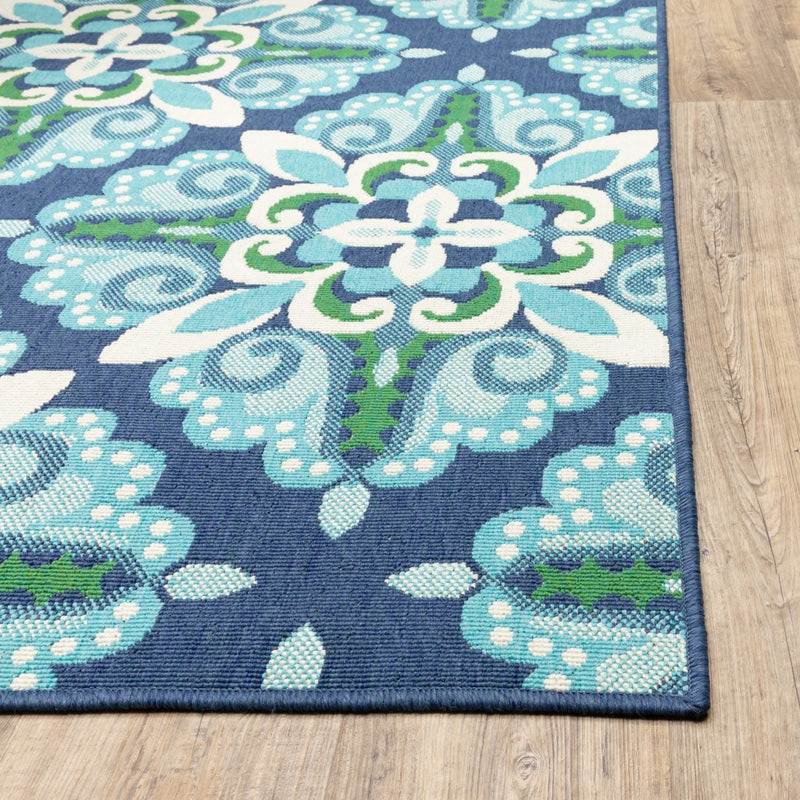 Indoor outdoor area rug corner detail with teal, green, and cream floral motifs on navy