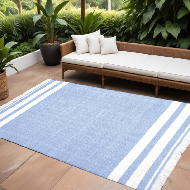 Light blue striped area rug with white bands and fringed edges on patio