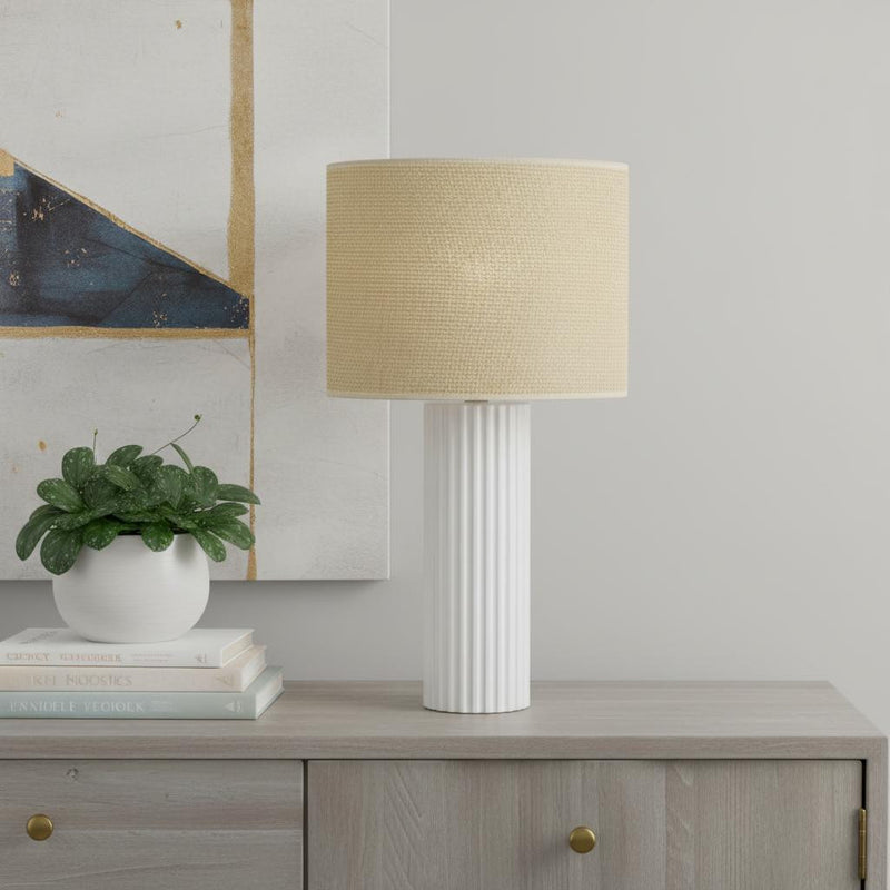 Table lamp on a console: beige drum shade with white fluted base.