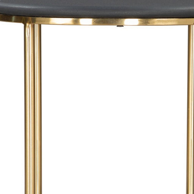 Close-up of a dark round tabletop edge with gold legs on a side table