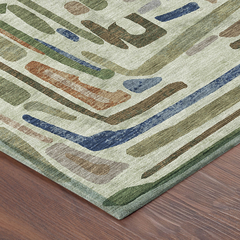 Edge corner of green abstract area rug showing drippy pattern and textured border.