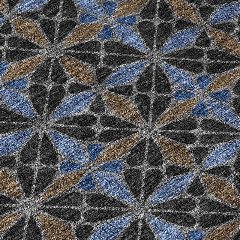 Geometric area rug close-up showing starburst shapes in dark gray, blue, and tan accents