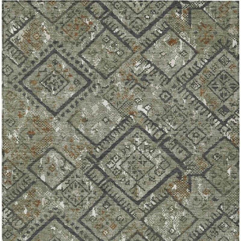 Green geometric area rug with diamond motifs, dark lattice lines, and scattered orange flecks