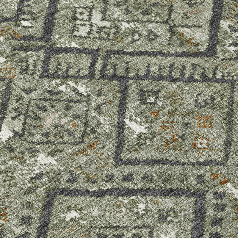 Detail view of green geometric rug pattern with interlocking diamond shapes and orange specks