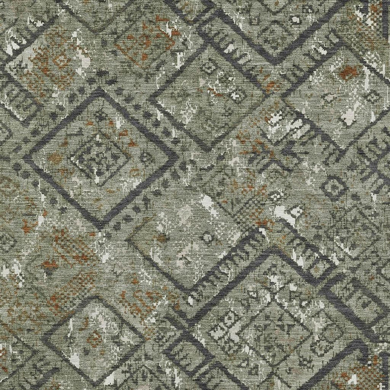 Close-up of green geometric rug showing diamond blocks, dark outlines, and orange speckles
