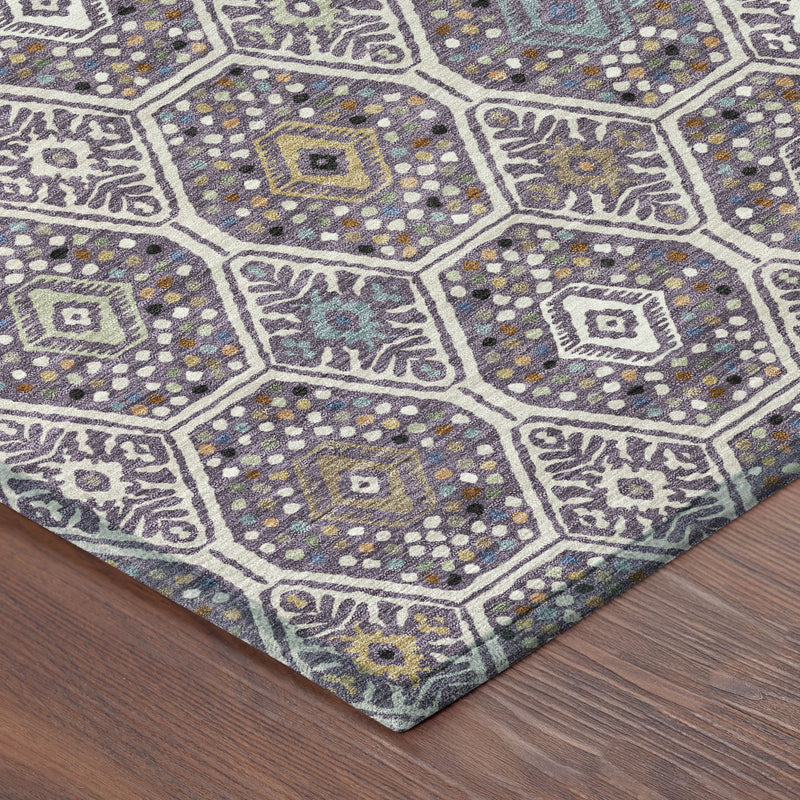Corner of geometric area rug with hexagon medallions in purple and blue on wooden floor