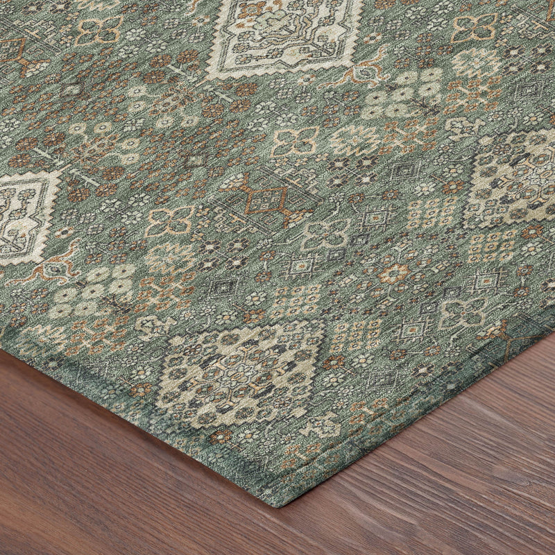 Corner of green and taupe geometric area rug with distressed motif and edging.