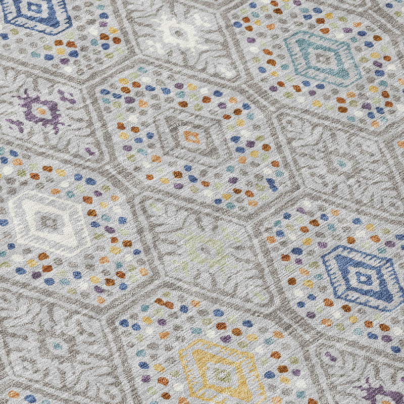 Close-up of geometric area rug pattern with blue, purple, and yellow dots on light gray