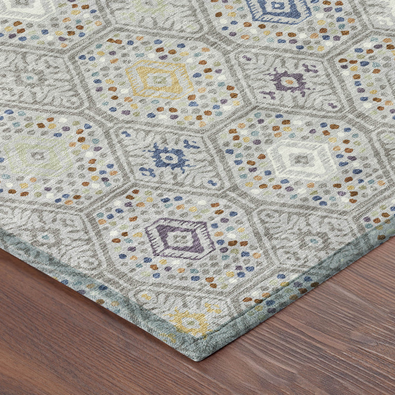 Corner of geometric area rug with multicolor diamond motifs on light gray pile