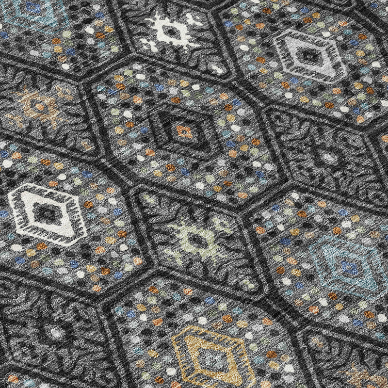 Round area rug close-up of weave: dark charcoal geometric design with teal and orange details