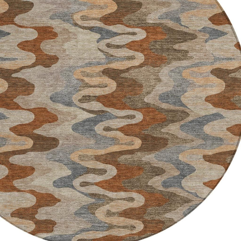 Round area rug close-up with wavy abstract design in tan, rust-brown, gray, and blue-gray