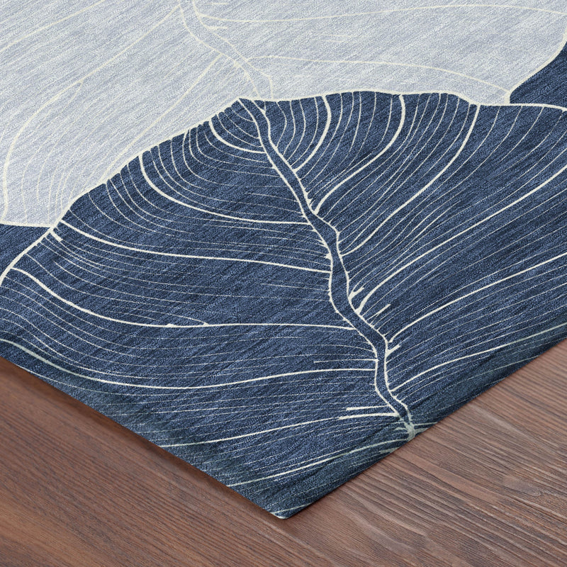 Navy and ivory leaf-pattern area rug corner on wood floor, flat woven surface.