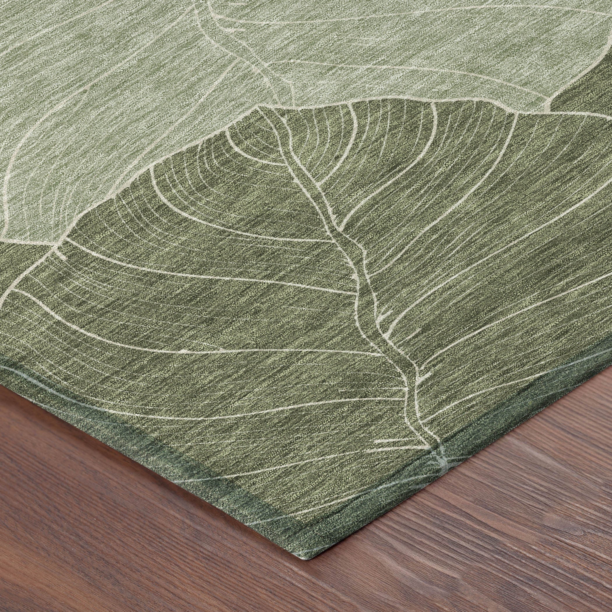 Olive green area rug corner with ivory leaf outlines and woven texture