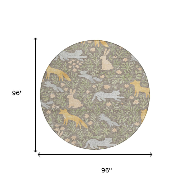 Round forest-themed area rug with taupe base, green leaves, and cream animal silhouettes