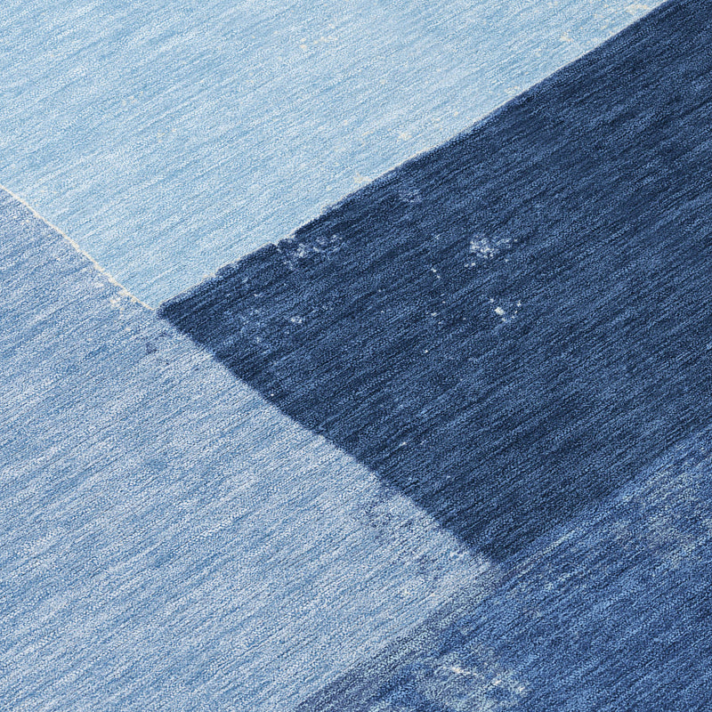 Blue geometric area rug close-up, textured low-pile fabric with dark border