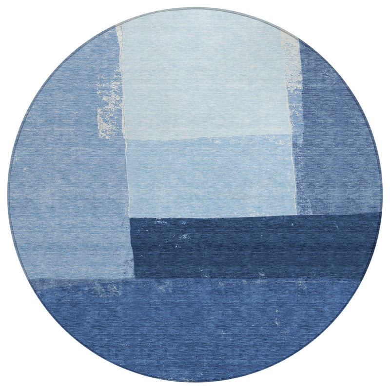 Round blue area rug with geometric patchwork, light center squares, and dark bands