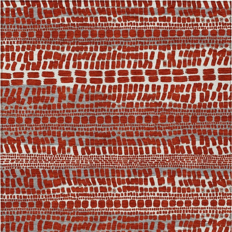 Red abstract area rug close-up, scattered brick-like blocks in white and gray.