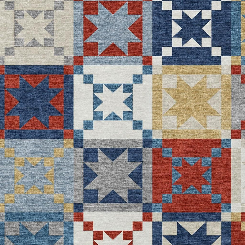 Patchwork indoor/outdoor area rug with geometric star squares in red, blue, gray, and cream.