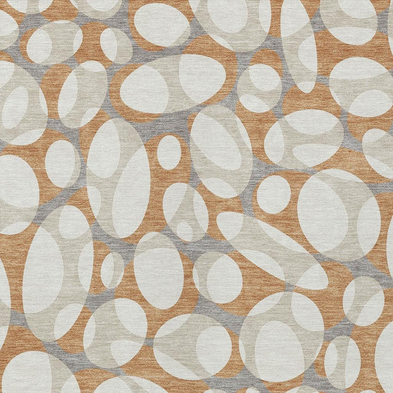 Close-up of abstract oval pattern area rug in ivory and copper over gray background