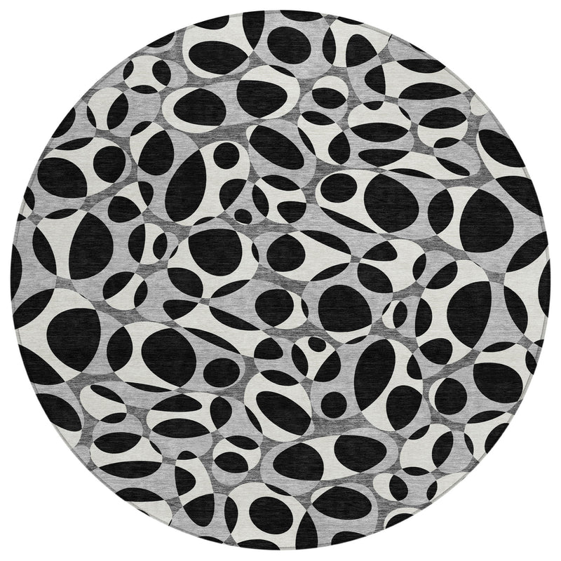 Round area rug featuring scattered black oval shapes on a light gray backdrop