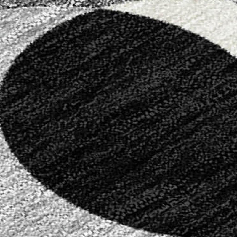 Black textured area rug corner, dark speckled pile and rounded border close-up