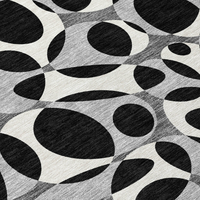 Close-up of black and gray oval abstract area rug pattern on a light base