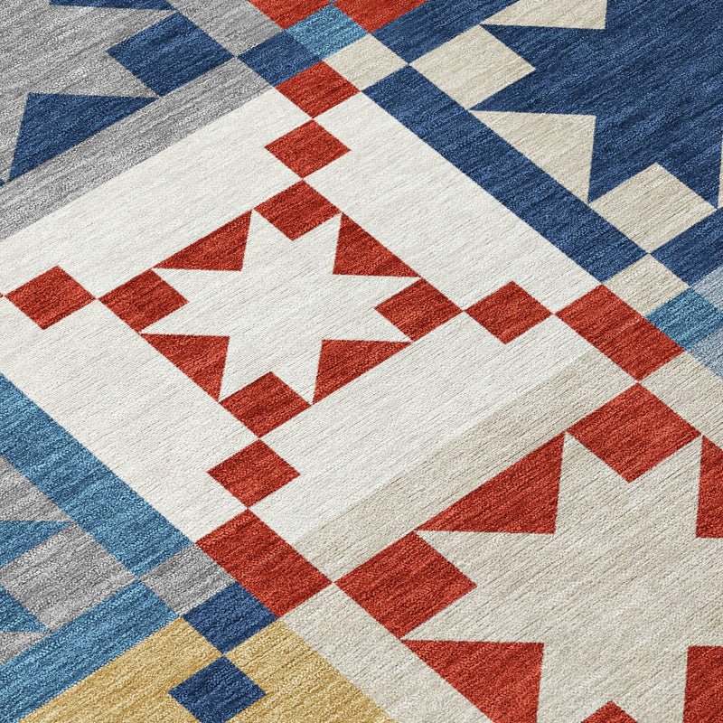 Patchwork area rug close-up: large white star with red diamonds and blue border on gray ground