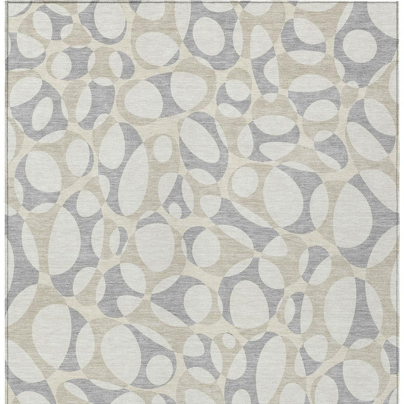 Indoor-outdoor area rug with repeating abstract oval pebble design in ivory and light gray