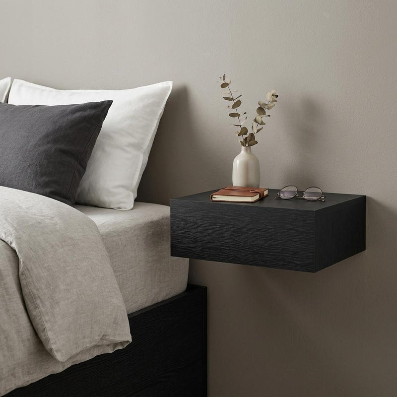 Black floating wood nightstand with single drawer and dark textured finish