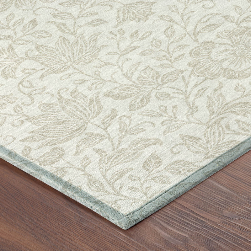 Corner view of ivory and beige floral area rug on wood floor with light border edge