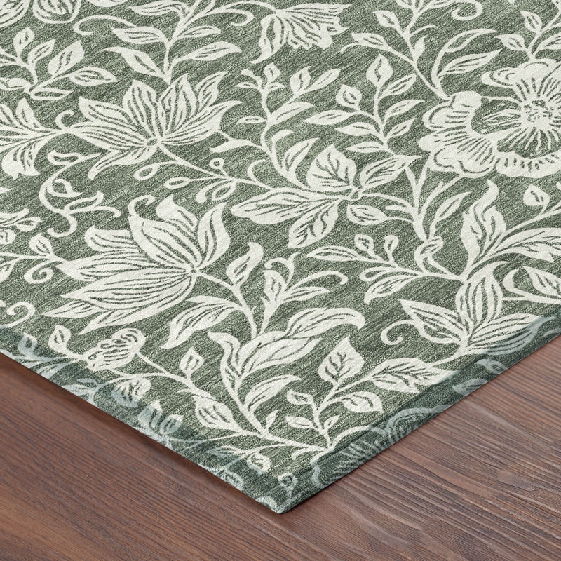 Green washable area rug with ivory floral pattern, corner shown on wood floor