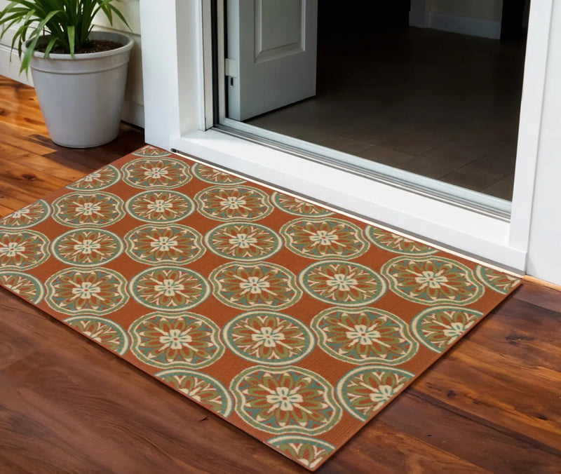 Orange floral patterned indoor/outdoor rug with intricate design, perfect for entryways and patios.