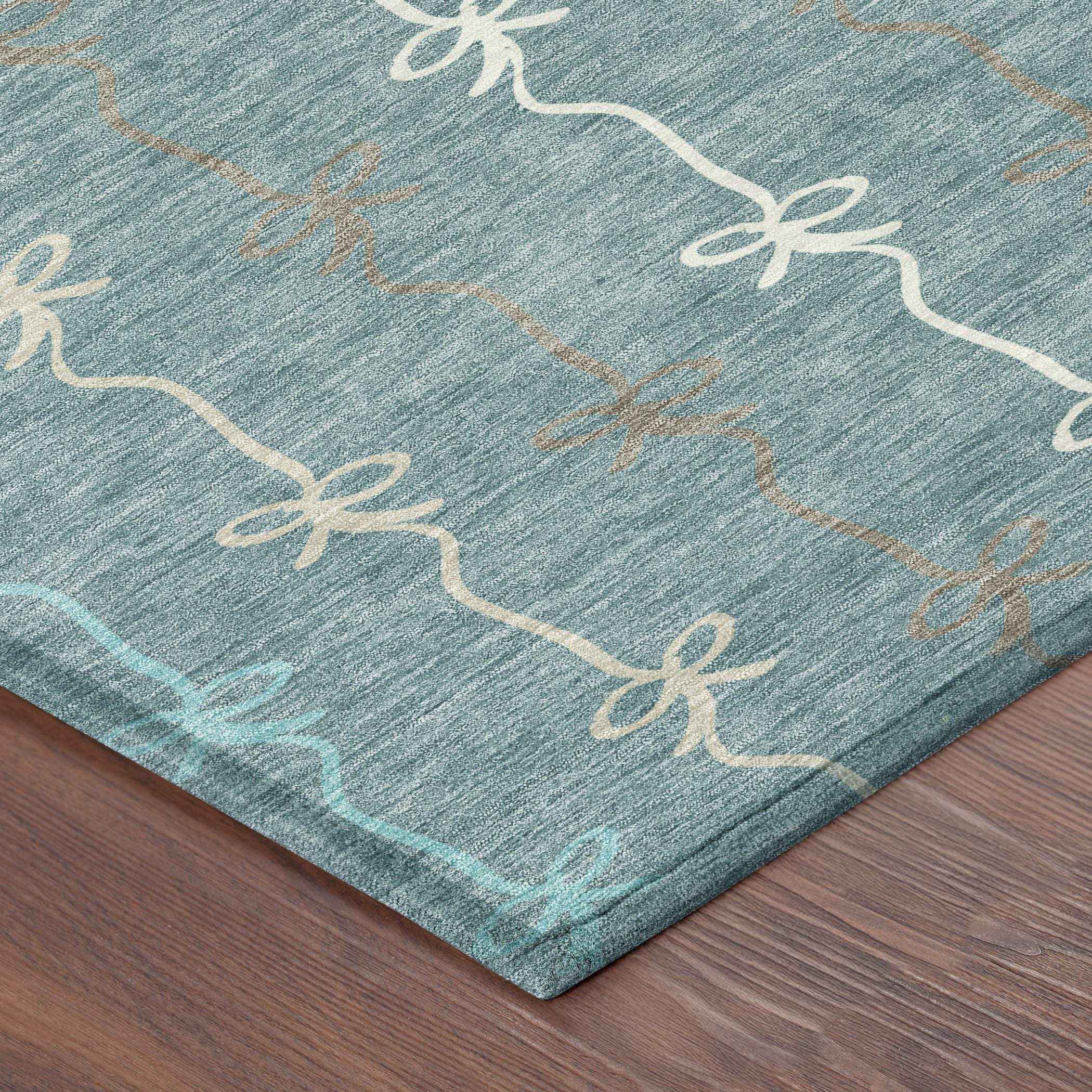 Teal area rug with beige and light blue bow patterns, soft fabric, perfect for modern home decor.
