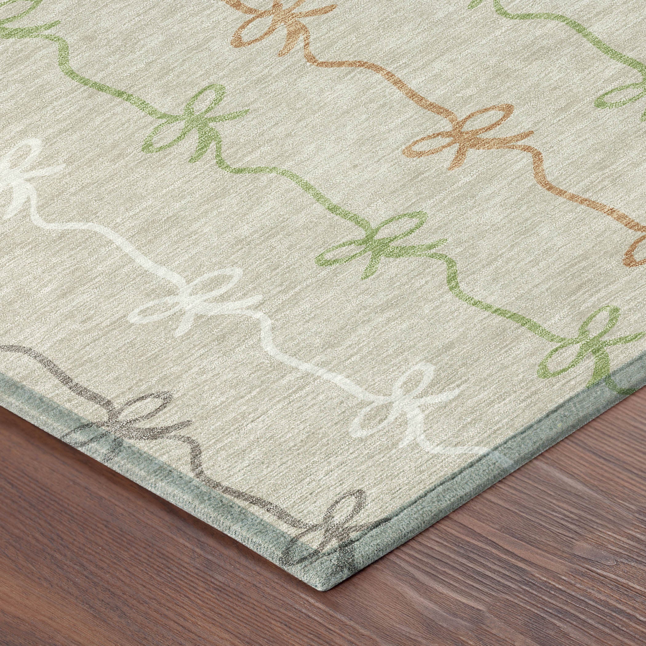 Tan area rug with green, orange, and gray bow patterns, crafted from soft, durable synthetic fibers.