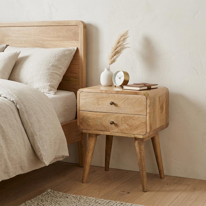 Oak two-drawer nightstand with round knobs and angled legs beside a bed