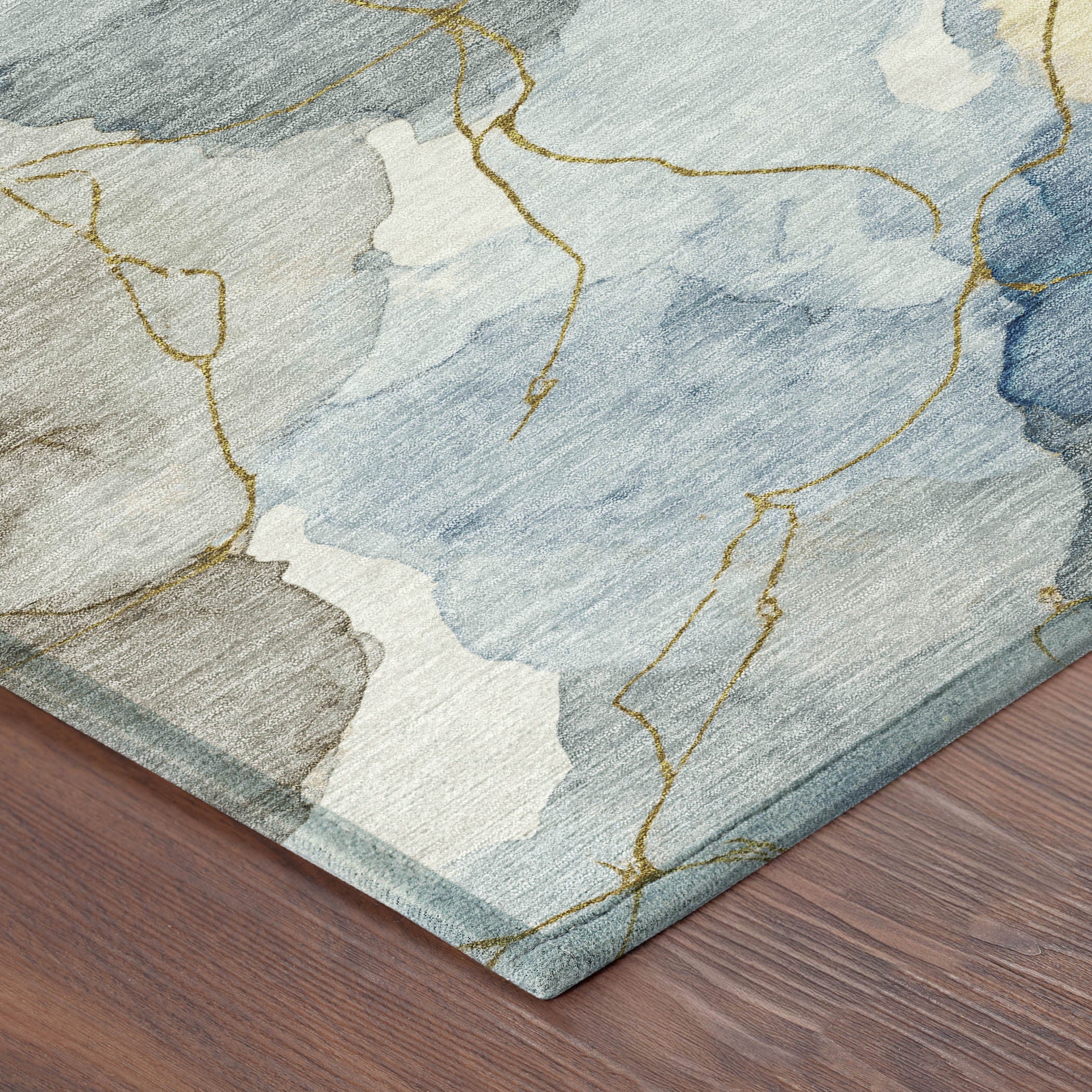 Blue and beige abstract area rug with gold accents on a hardwood floor, perfect for modern decor.