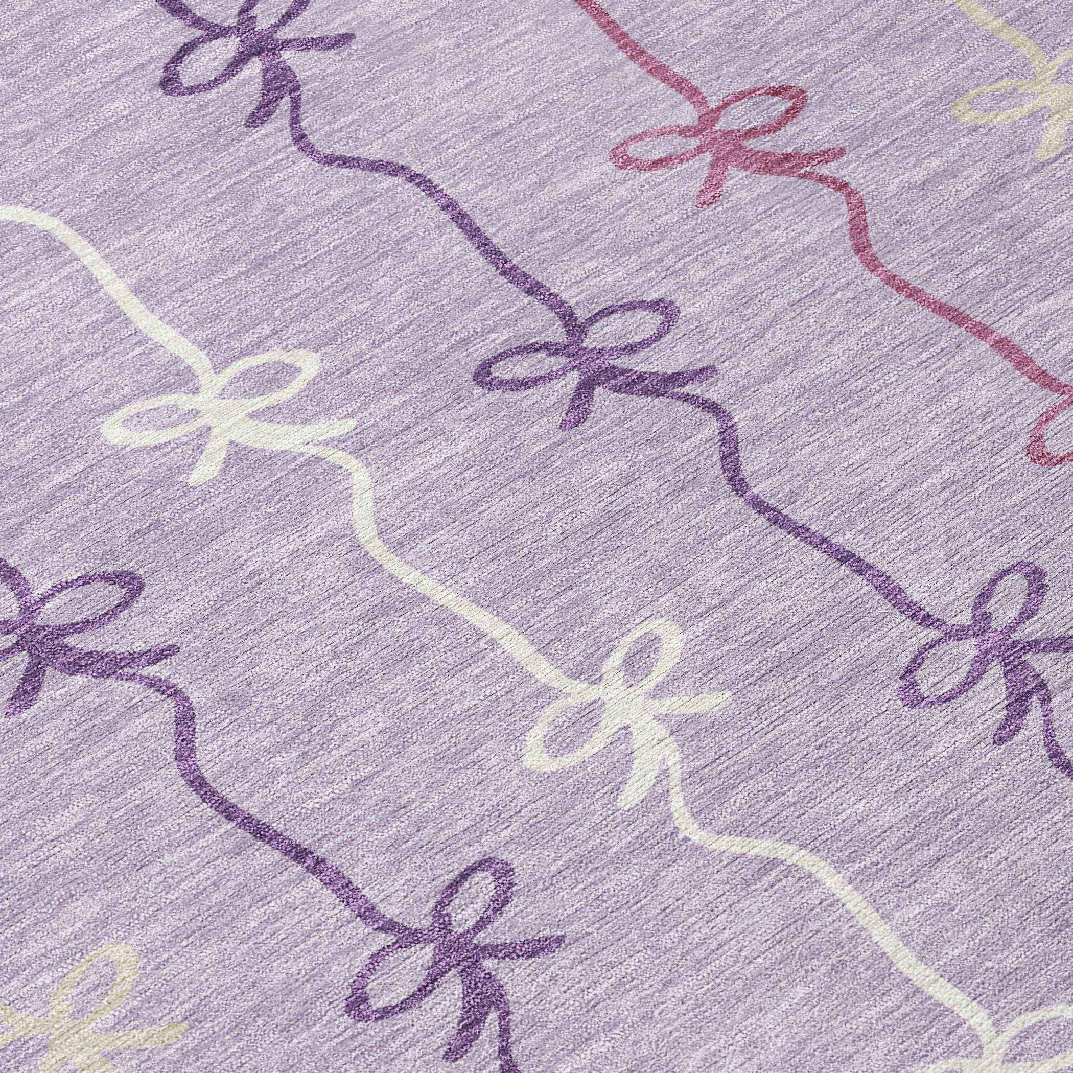 Lavender fabric with pastel ribbon pattern, featuring pink, purple, and cream bows, perfect for crafting or home decor.