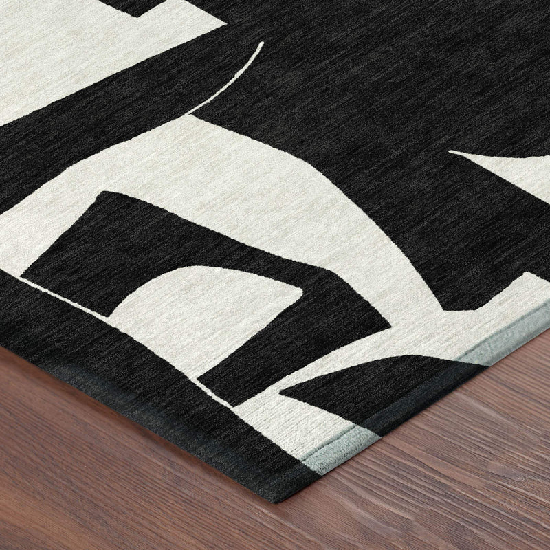 Geometric area rug corner with black and ivory abstract blocks on dark ground