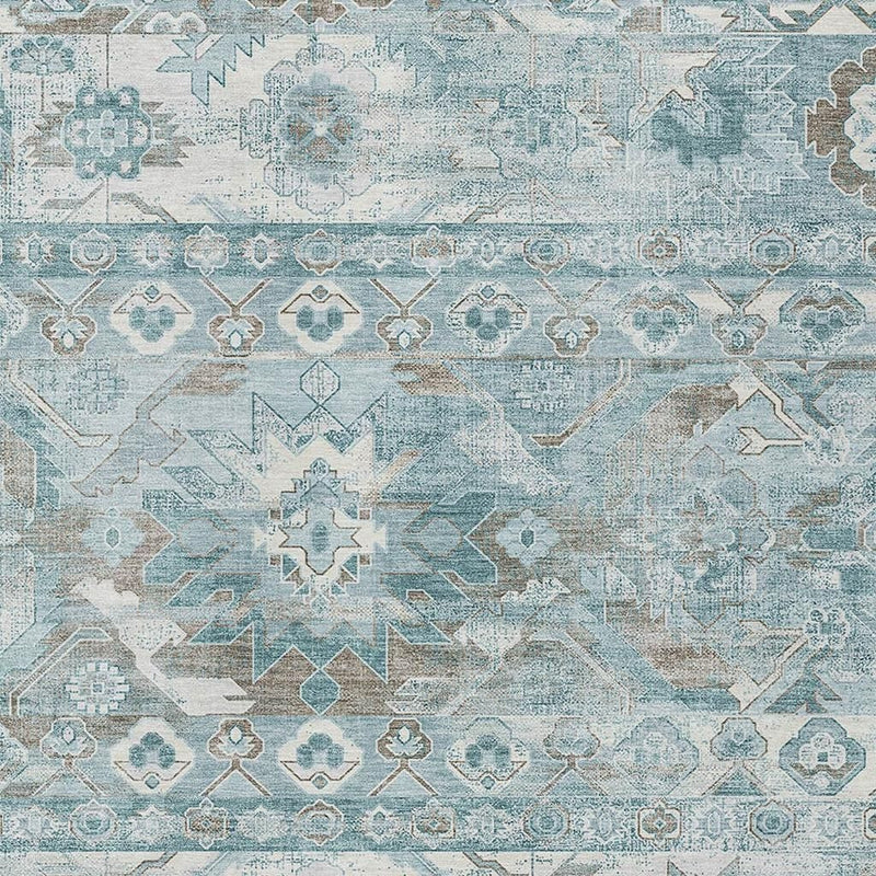 Close-up teal and silver area rug with framed medallions and geometric lines.