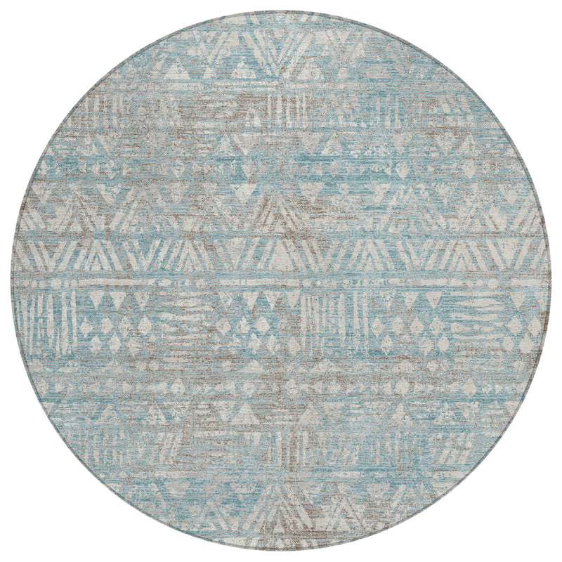 Round area rug with teal-blue and pewter geometric motif and distressed textured surface