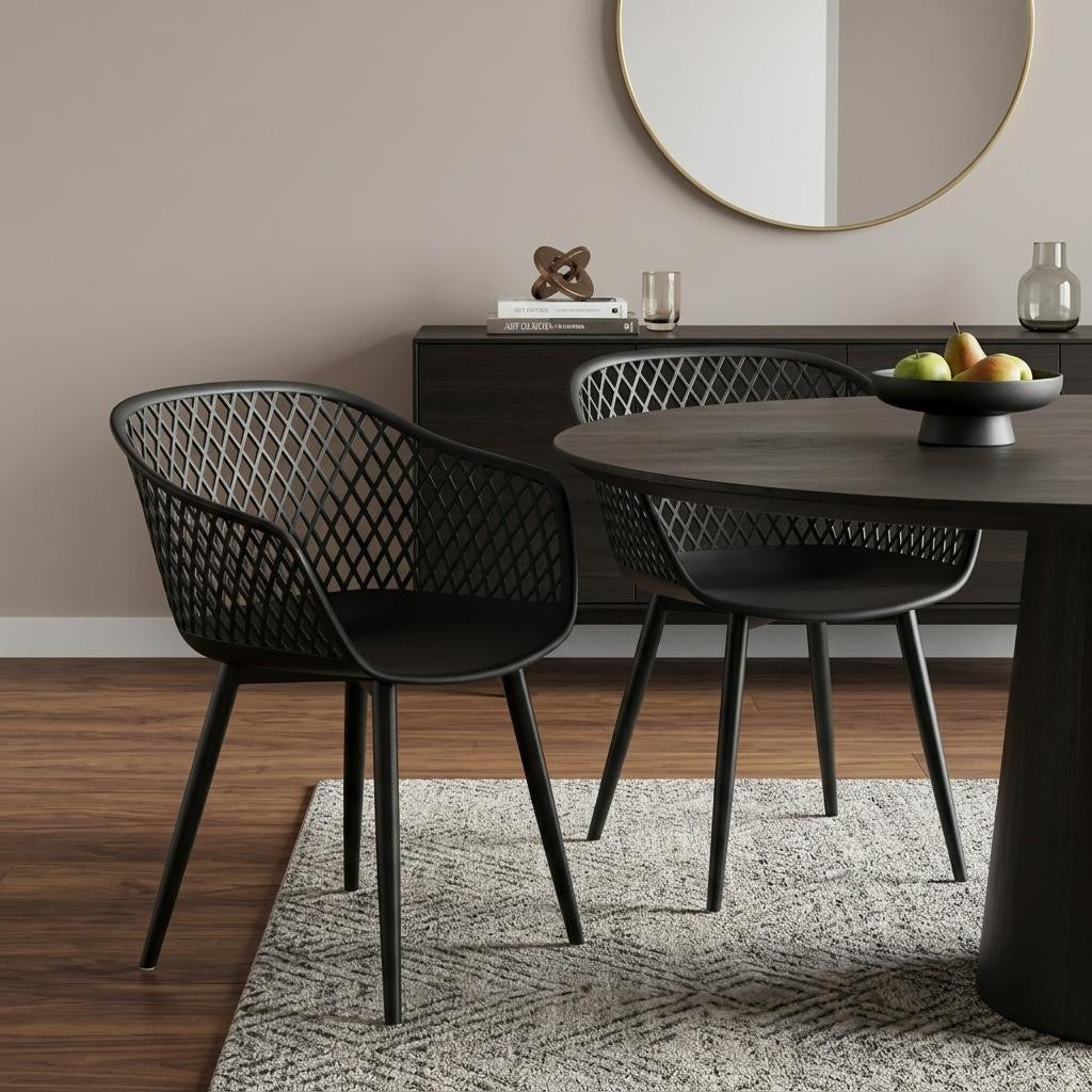 Set of two black plastic outdoor stacking chairs at a dining table with lattice backs