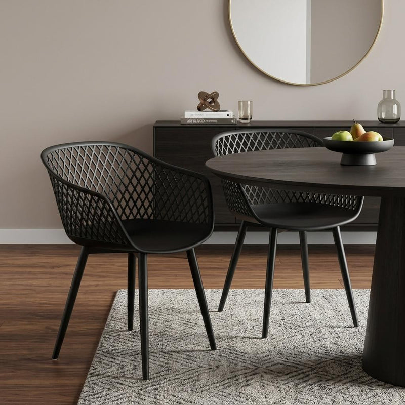 Set of two black plastic outdoor stacking chairs at a dining table with lattice backs