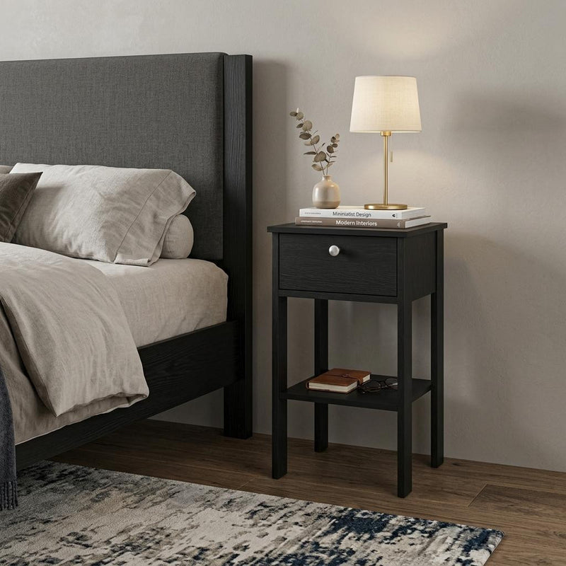 Black one-drawer nightstand with open shelf, silver knob; lamp on top