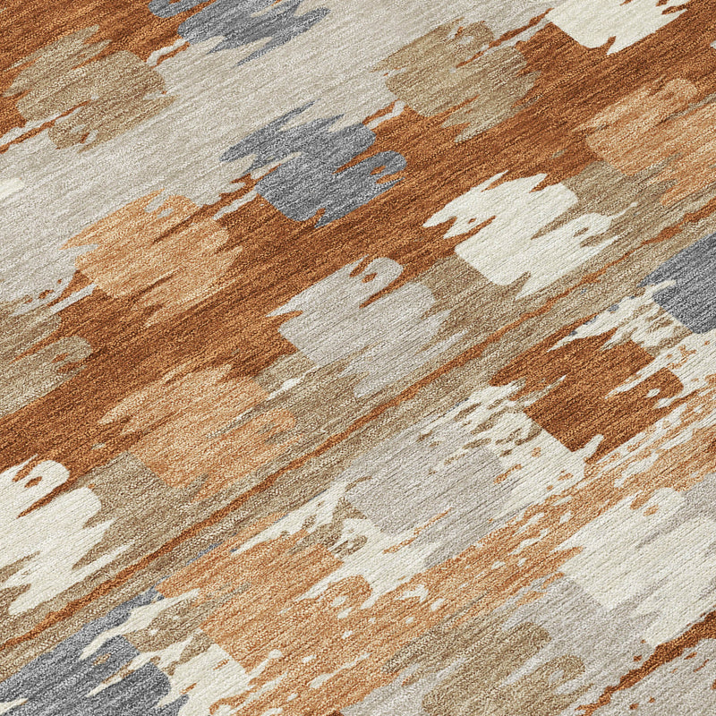 Abstract area rug close-up with rust orange, beige, and gray streaked blocks.