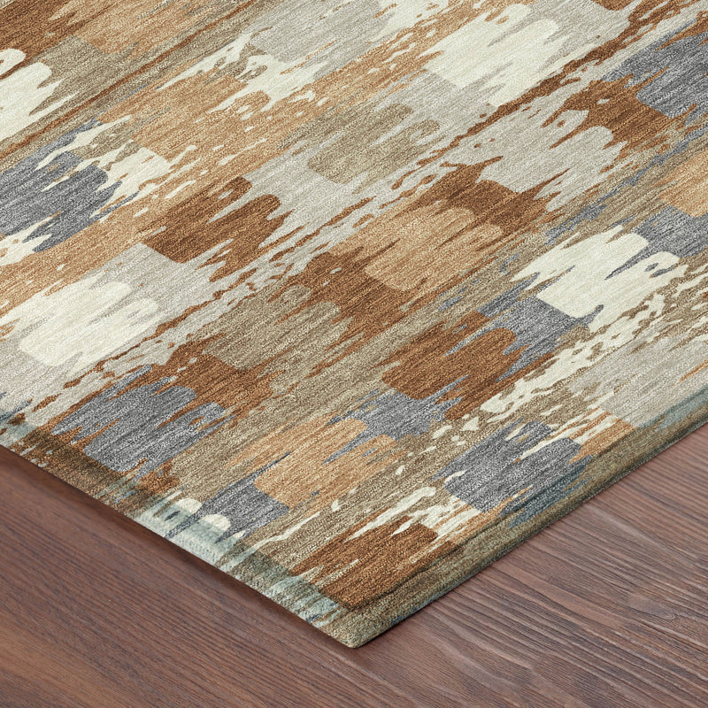 Corner view of abstract area rug with orange, beige, cream, and gray pattern.